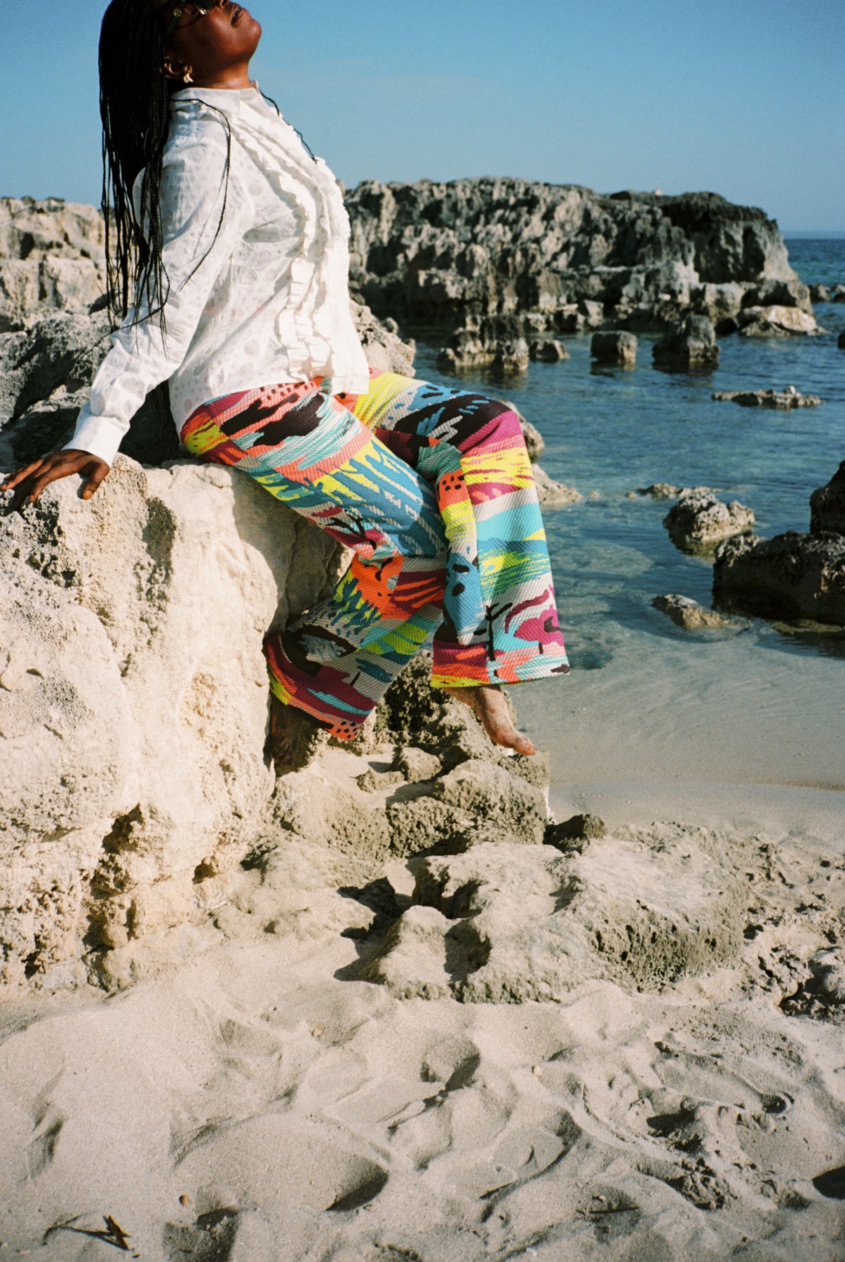Scan 04 — white burnout ruffle top and electric horizon pants on coastal rock