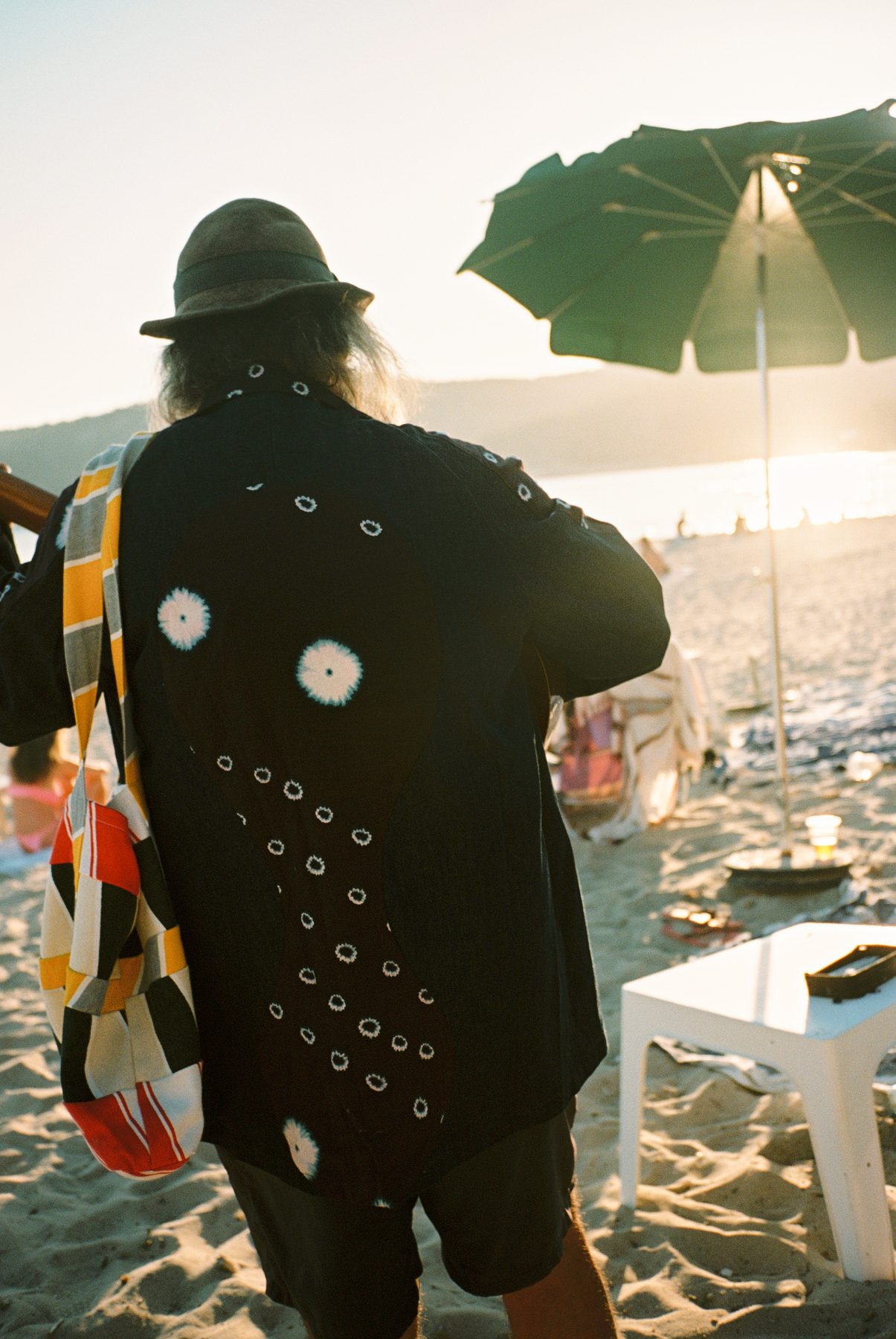 Scan 17 — black sunburst-dot shirt and patchwork tote, parasol at golden hour