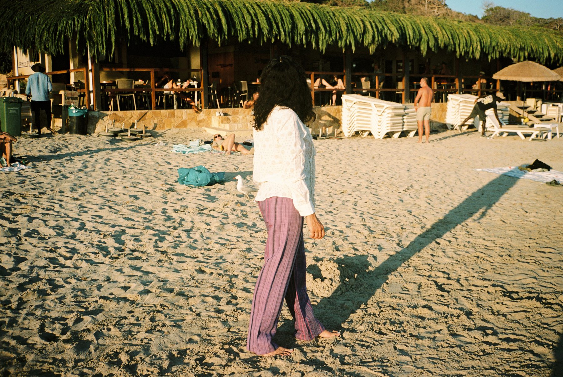 Scan 26 — white burnout ruffle top and shibori indigo trousers, crossing the sand